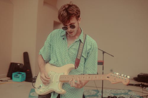 Kostenloses Stock Foto zu elektrische gitarre, gitarrist, grünes shirt