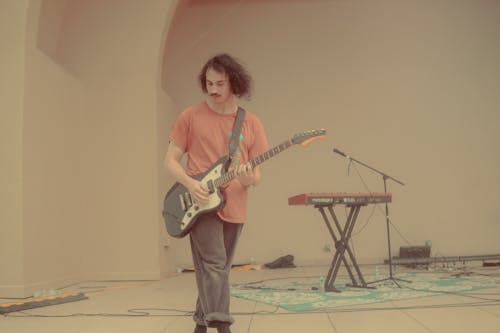 Man in Pink T-Shirt Playing an Electric Guitar on a Stage