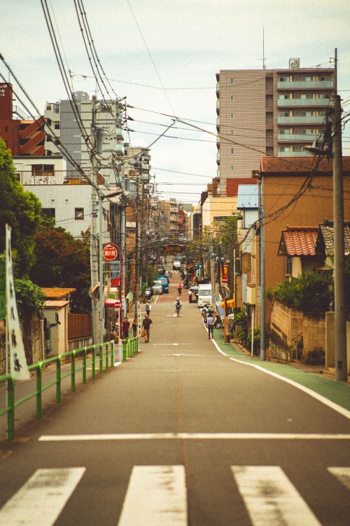 Free A street in Tokyo, Japan, featuring buildings, power lines, and cyclists in an urban setting. Stock Photo