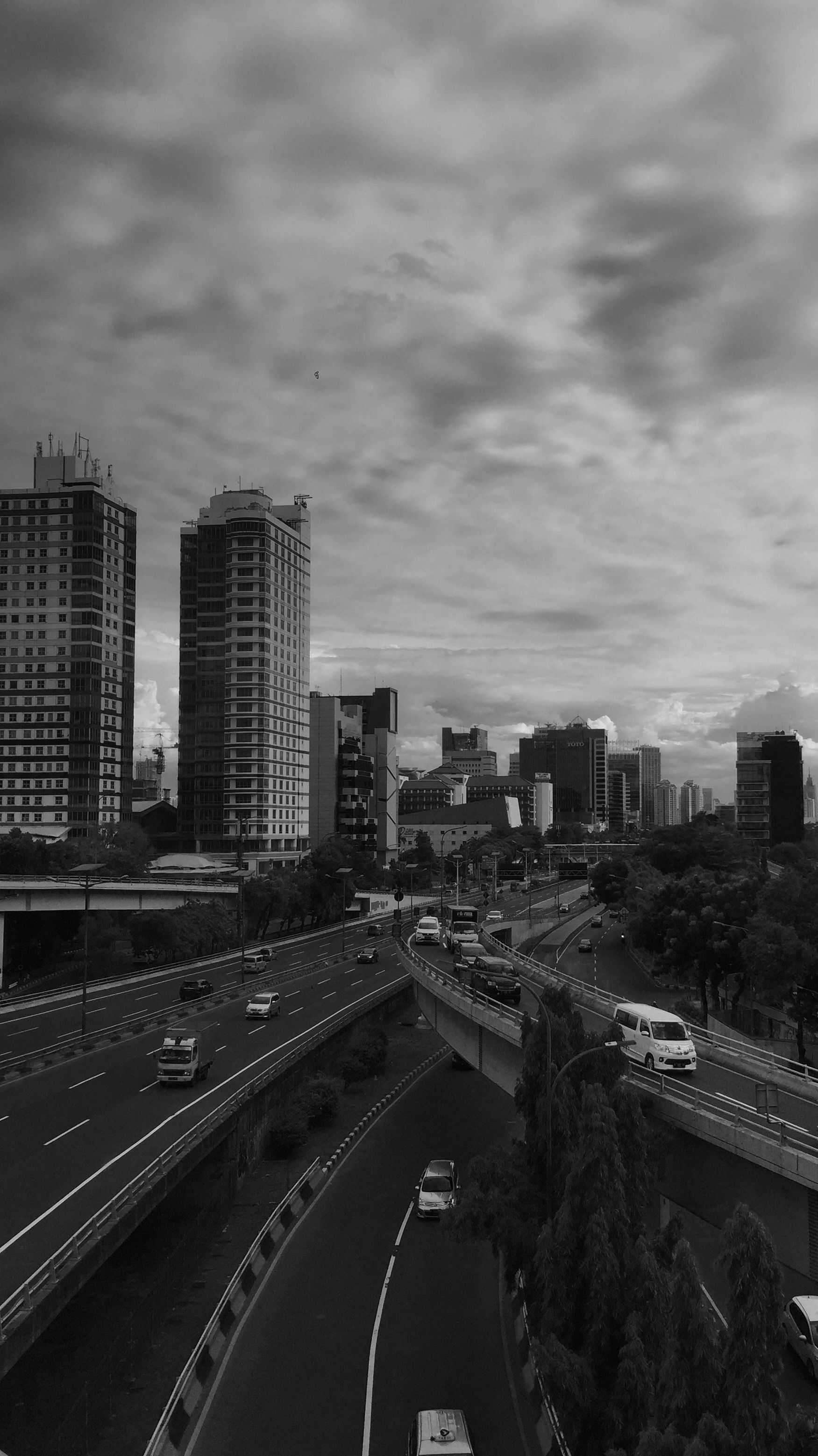 Urban Jakarta scene showcasing busy highways and high-rise buildings under an overcast sky.