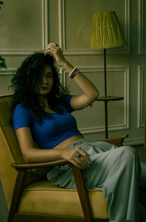 Photo of a Woman Wearing a Blue Blouse Sitting in an Interior
