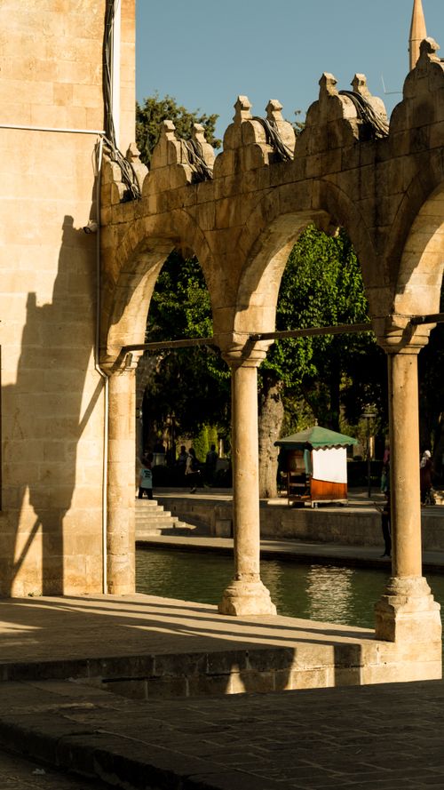 Free Elegant Ottoman arches overlook a peaceful canal under the warm sunlight, highlighting rich historical architecture. Stock Photo
