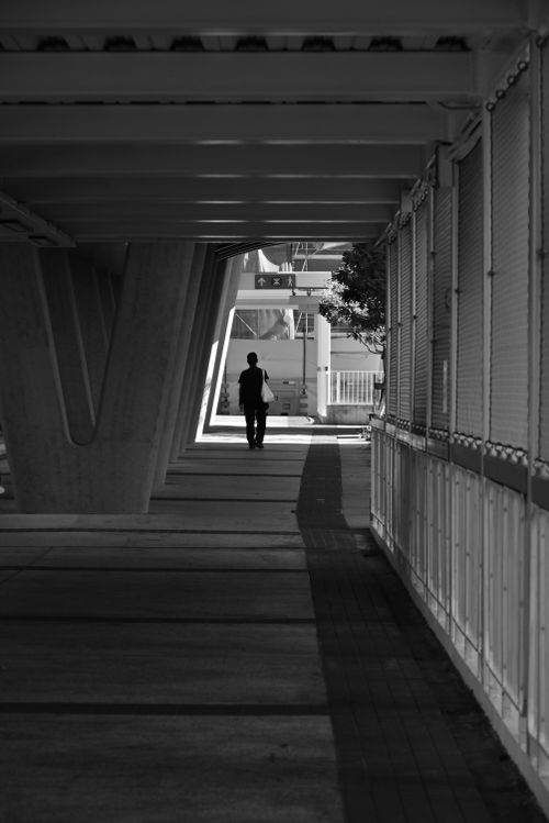 Free Silhouette of a person walking on a modern bridge in a city, captured in black and white. Stock Photo