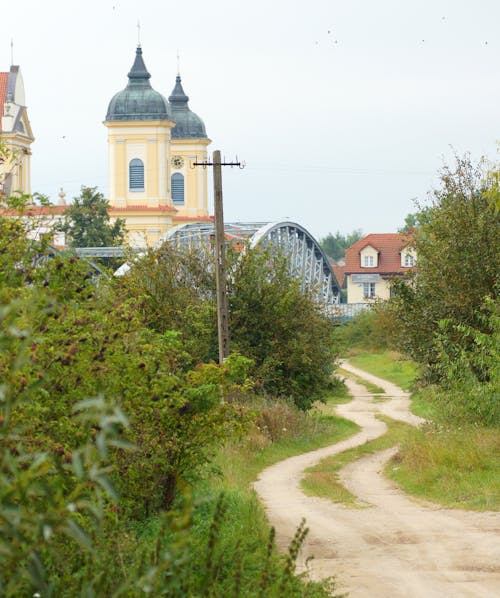 Dirt Road and Church Towers in Village behind