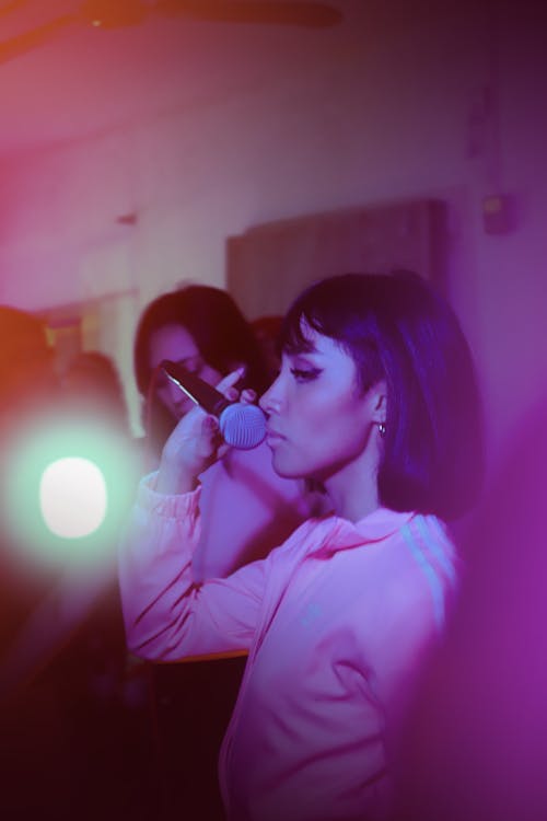 Young Brunette Woman in Pink Track Top Holding a Microphone