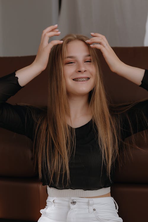 Smiling Blonde Woman Sitting and Fixing Hair