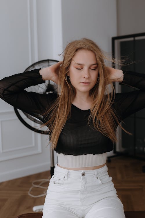 Blonde Woman Fixing Hair with Eyes Closed