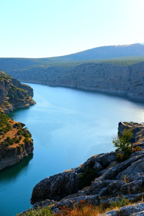 Free Breathtaking view of a serene river flowing between majestic cliffs under a clear sky. Stock Photo