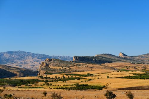 Free A serene view of rolling hills and countryside under a clear blue sky. Stock Photo