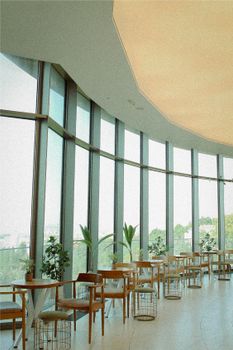 Spacious restaurant interior featuring large windows and modern decor with plants and tables.