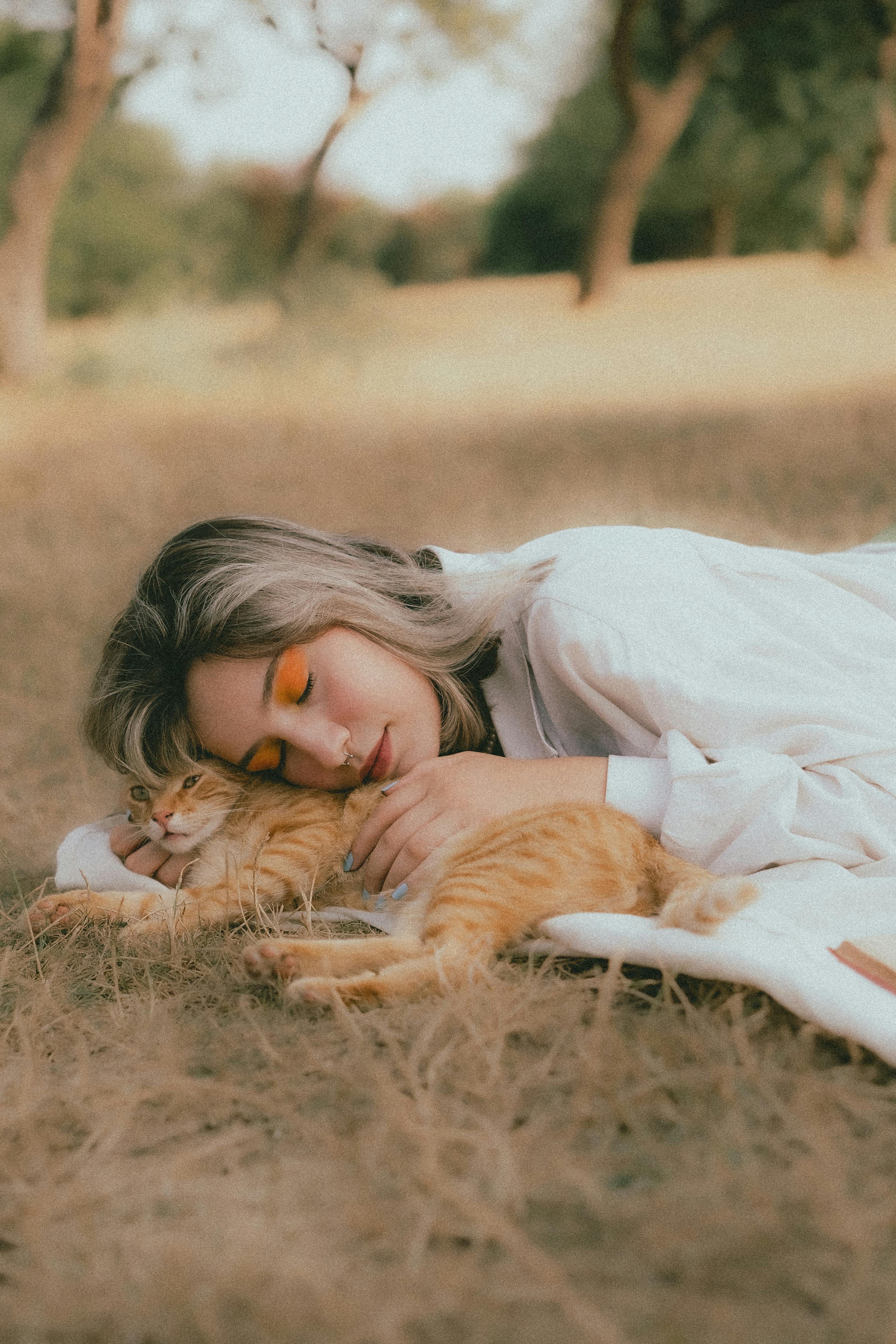 woman lying down with cat on grass