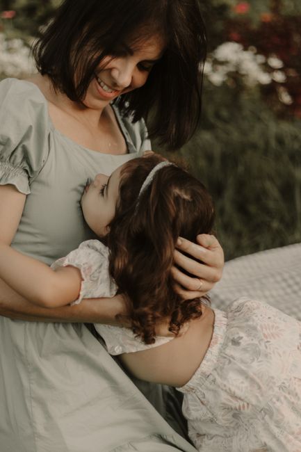 A joyful mother and daughter embrace in a lush garden setting, capturing a moment of affection and happiness.