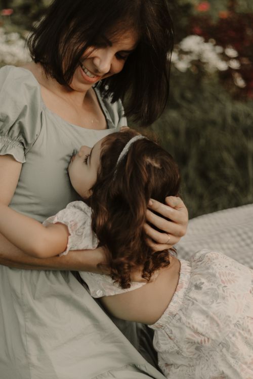Free A joyful mother and daughter embrace in a lush garden setting, capturing a moment of affection and happiness. Stock Photo