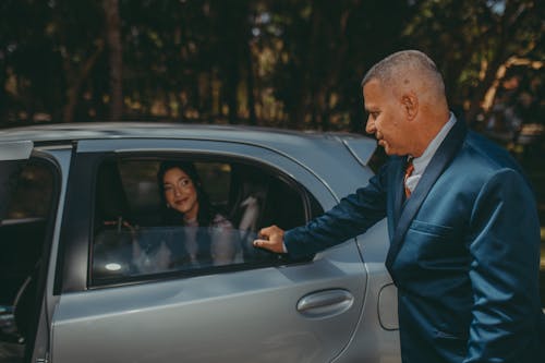 Man Standing by Car with Woman Sitting in