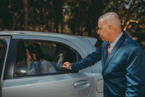 Man in Suit Standing near Silver Car