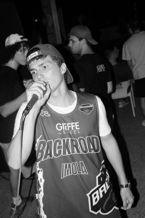 Free Black and white photo of a young man singing into a microphone at a nighttime gathering. Stock Photo