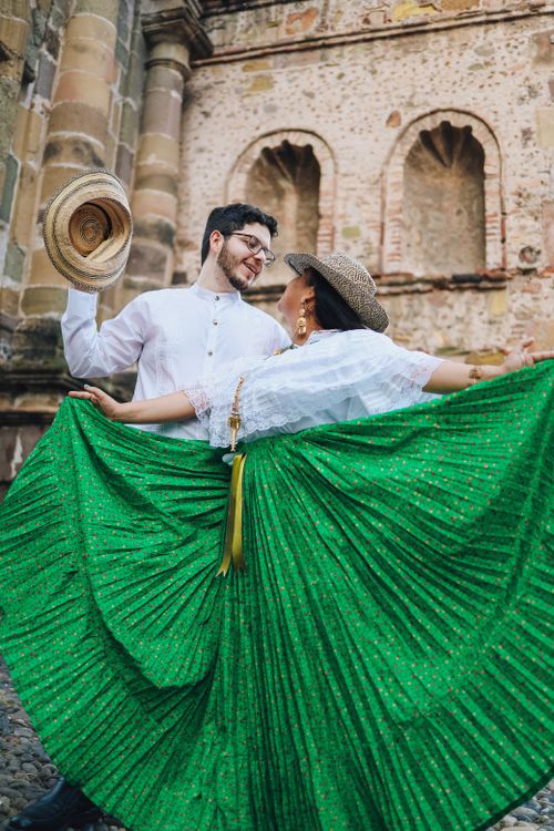 Free Man and woman in traditional attire dancing joyfully outdoors. Stock Photo