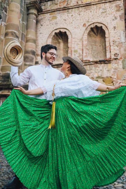 A joyful couple in traditional Latin attire dances passionately in a historic outdoor setting in Panama.
