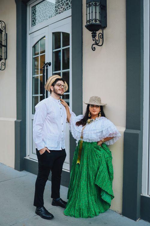 Free A couple in traditional clothing stands elegantly by an ornate entrance, evoking cultural richness and urban style. Stock Photo