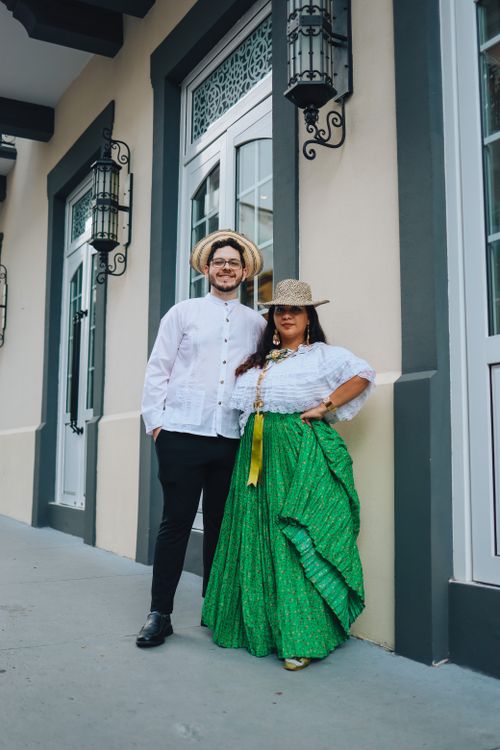 Free A couple wearing traditional outfits posing on a vibrant city street, exuding cultural charm. Stock Photo