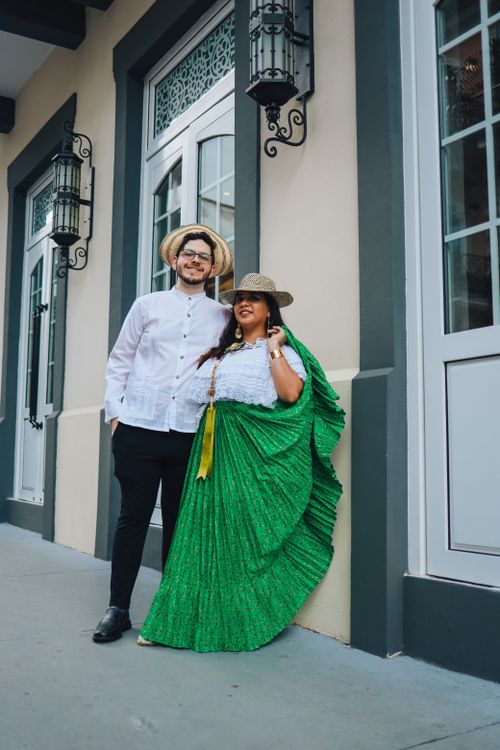 Free A couple in traditional clothing poses cheerfully on a city street with elegant architecture. Stock Photo
