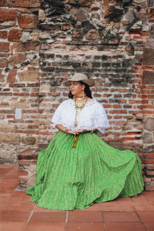 Free Woman in a traditional white blouse and green skirt at rustic brick wall. Stock Photo