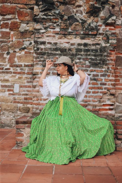 Free Elegant woman in traditional attire posing by a rustic brick wall. Stock Photo