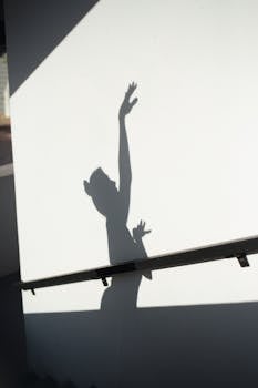 Shadow of a dancer gracefully extending arms along a wall, creating a striking silhouette.