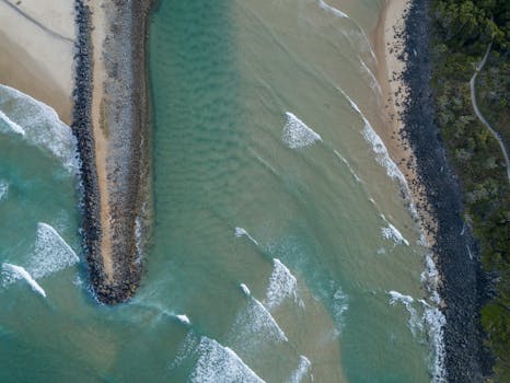 A stunning aerial view of a rocky coastline with waves crashing onto the shore.