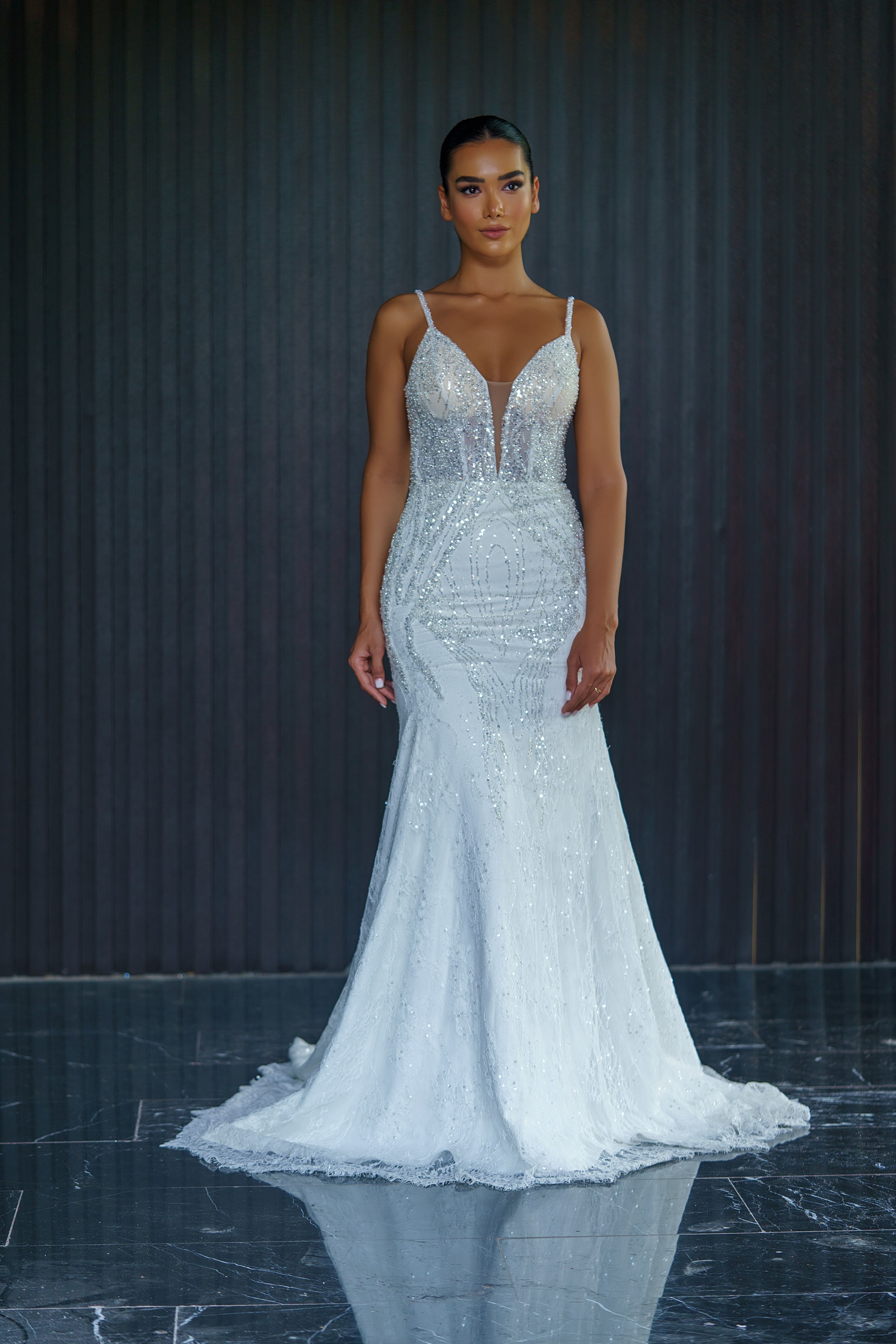 Glamorous full-length portrait of a woman in an elegant bridal dress posing indoors.