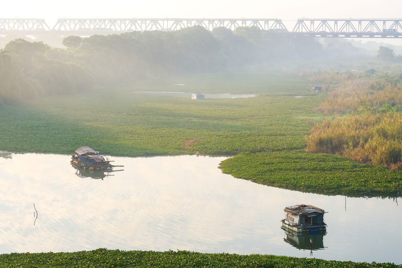 serene river landscape with barges and a foggy railway bridge