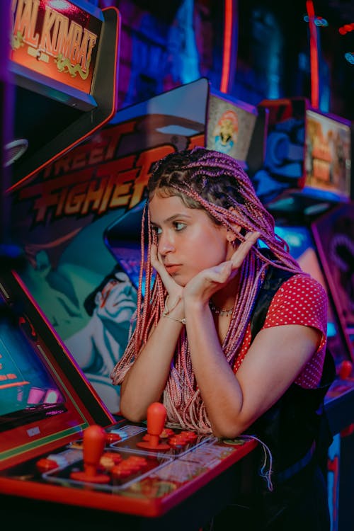 Young Woman Standing beside a Machine in an Arcade 