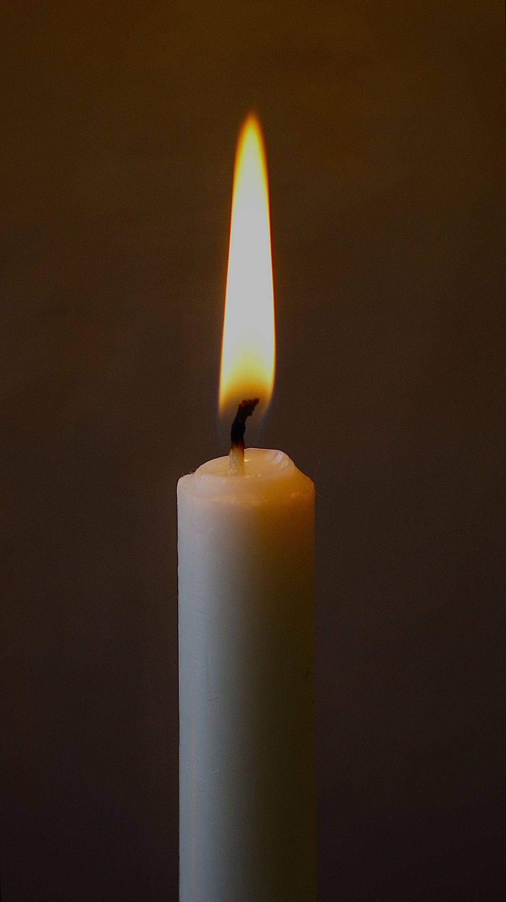 A single lit candle in a quiet, dark room