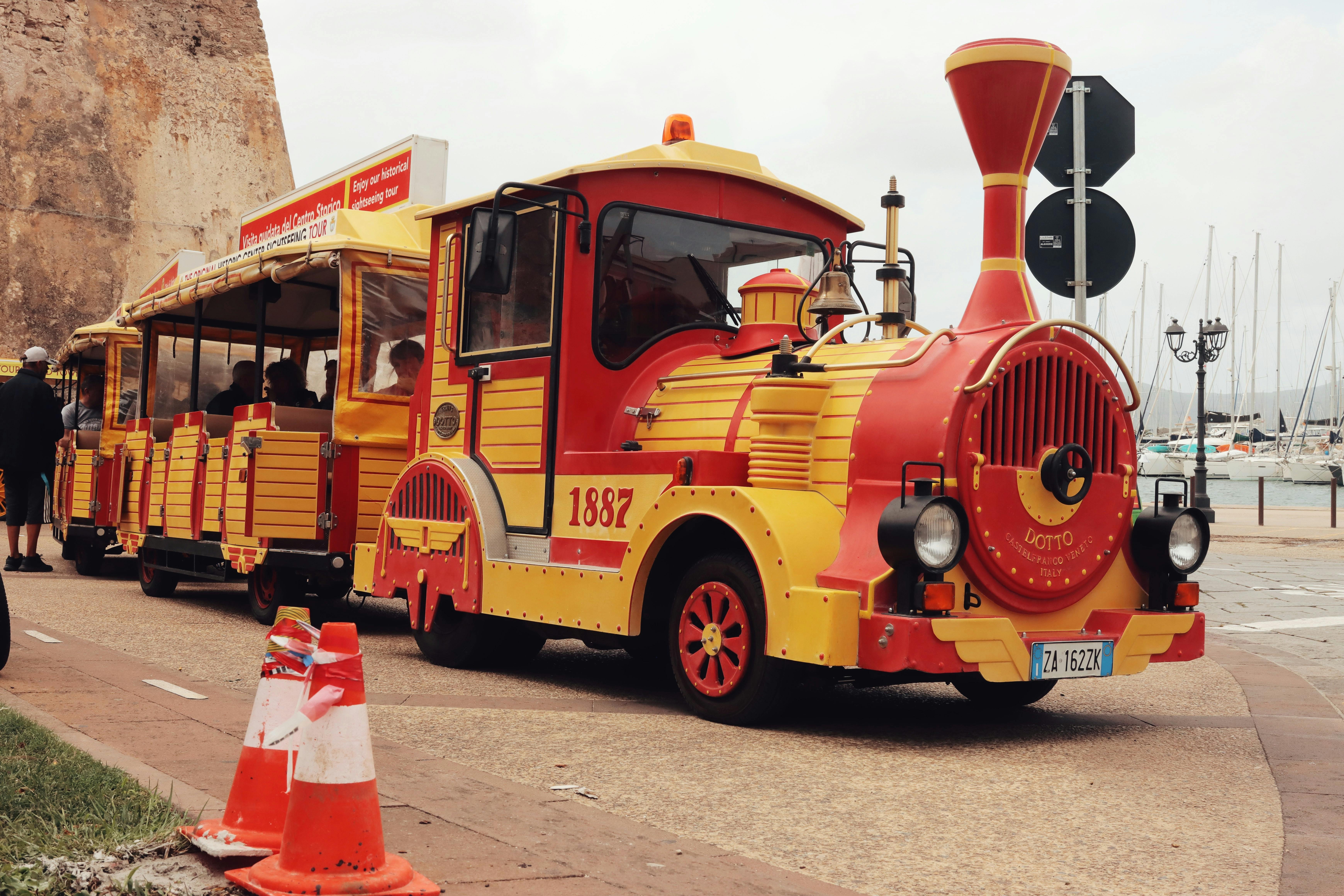 Un vibrante tren turístico con diseño vintage en las calles de Alghero, Cerdeña, Italia.