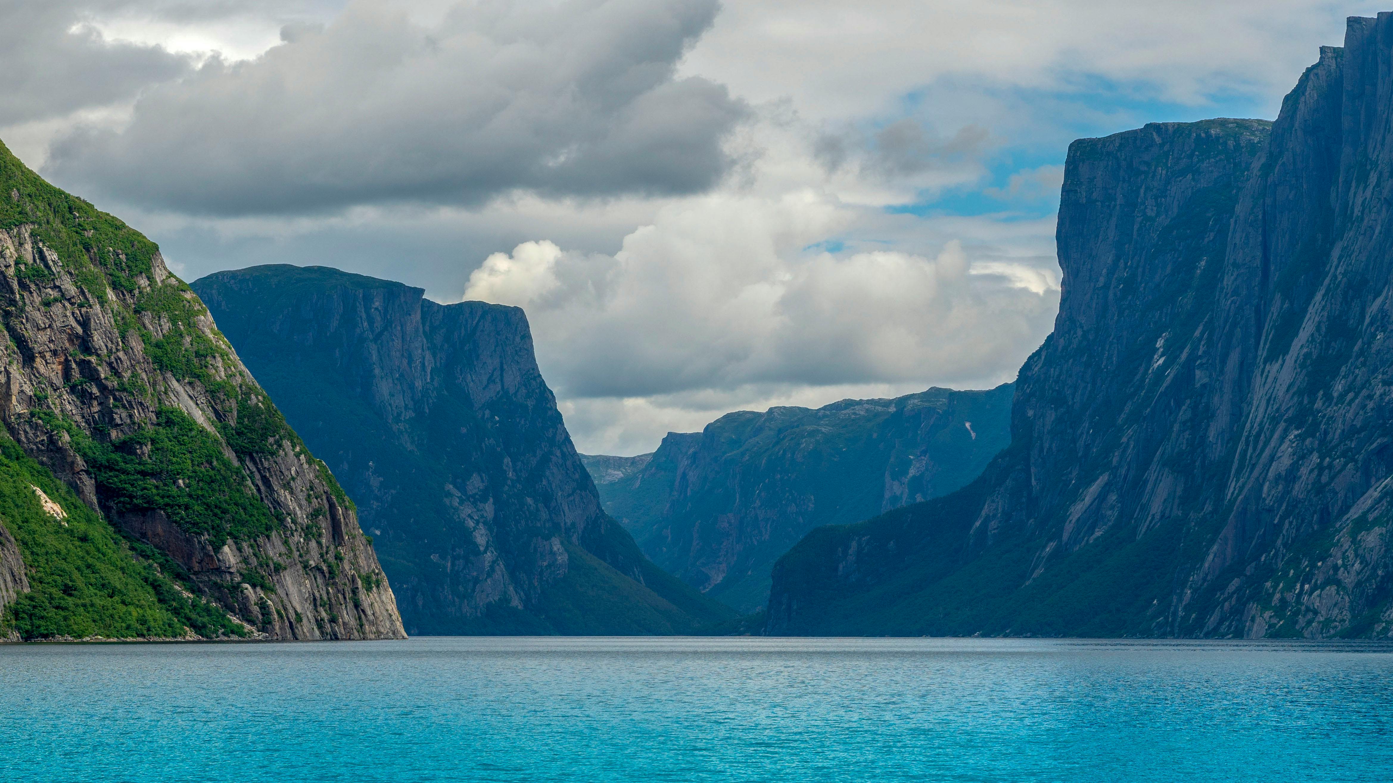 Rocky shoreline with clear water and mountain peaks in bright daylight