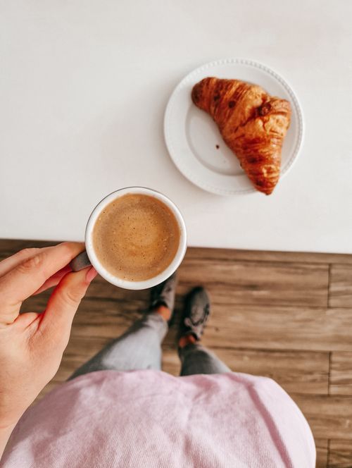 Free Enjoy a cozy breakfast with coffee and a croissant served on a white table, captured from above. Stock Photo