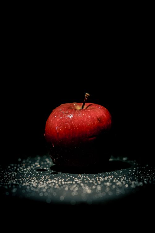 Free Close-up of a red apple with water droplets on a dark studio background, highlighting its freshness. Stock Photo