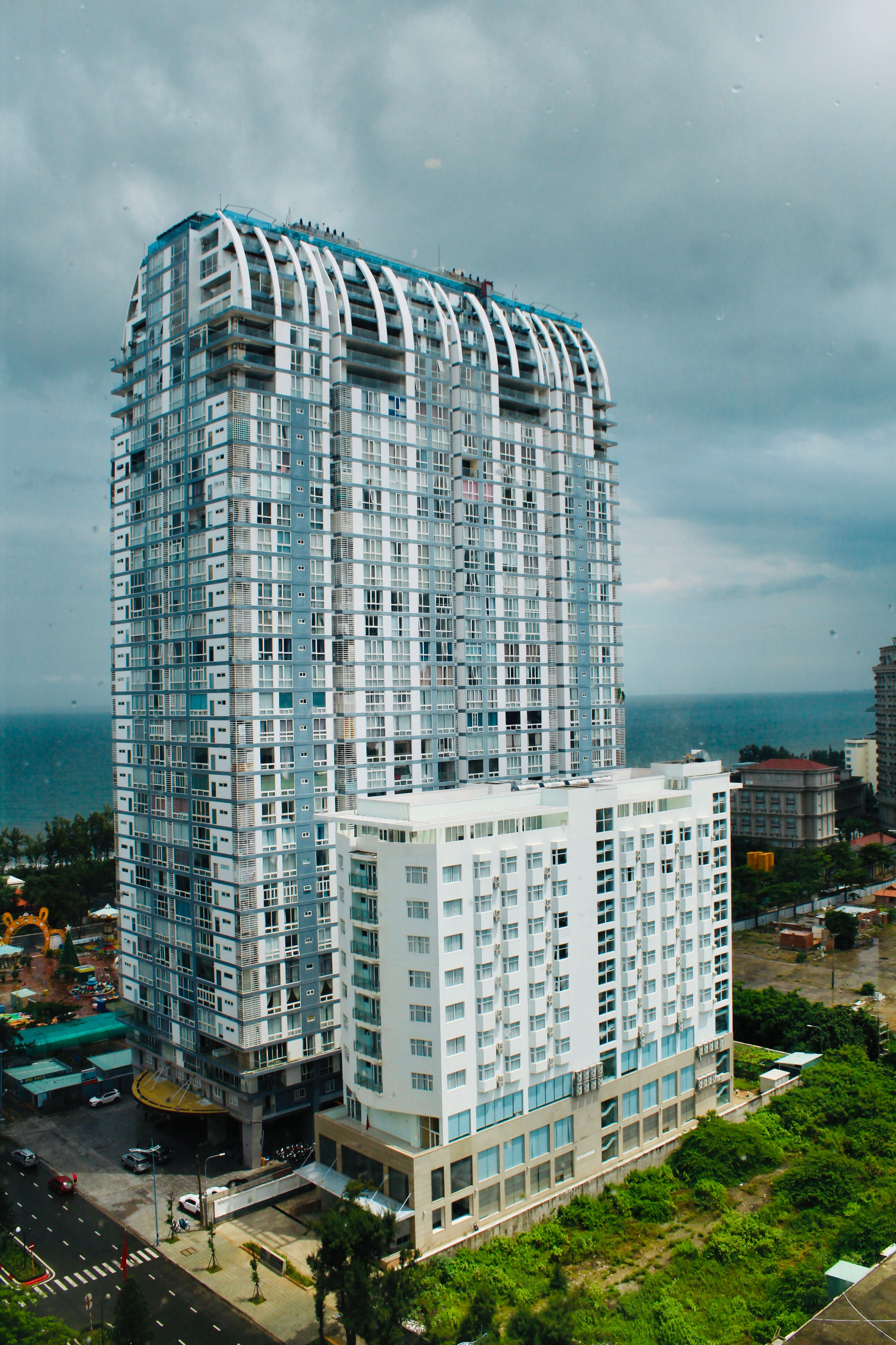 Urban skyscraper with coastal view, cloudy sky creating a dramatic atmosphere.