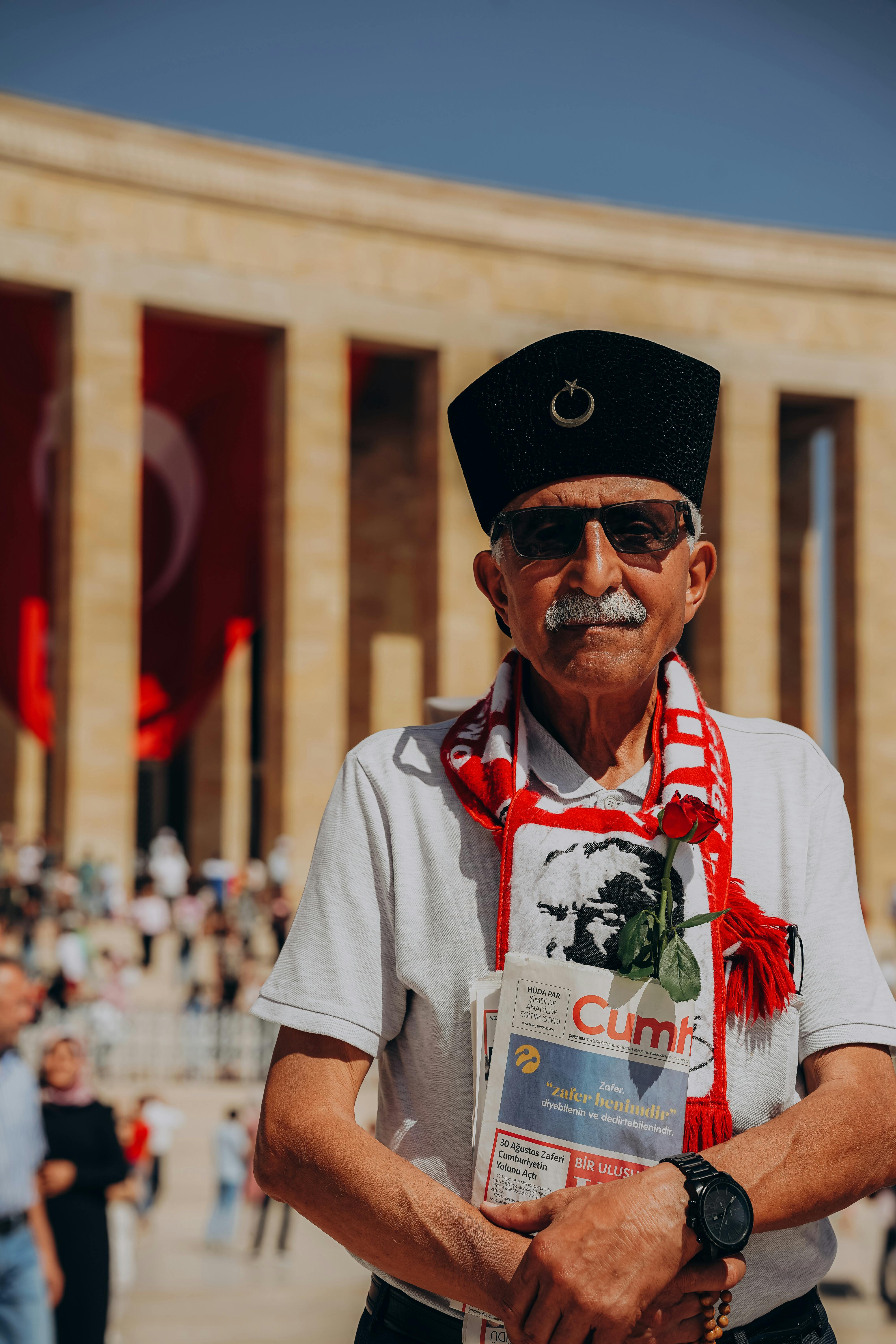 Senior man holding newspaper at Anıtkabir, Ankara, showcasing patriotism and style.
