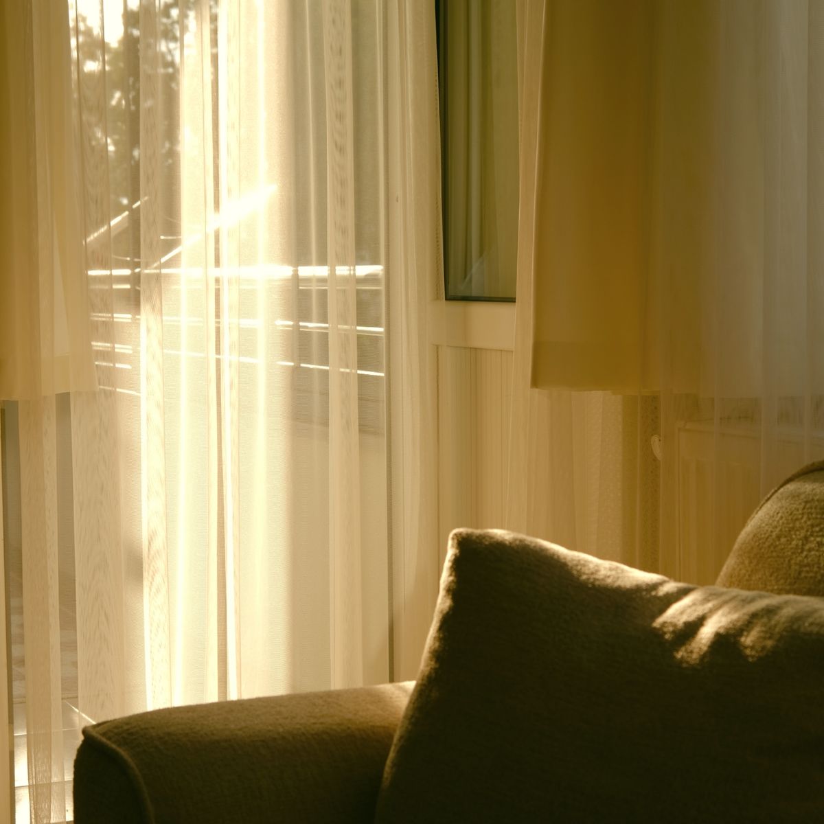 Sala de apartamento com luz solar atravessando a cortina