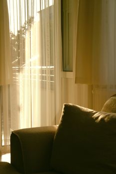 A serene indoor scene with sunlit curtains and a comfortable sofa, perfect for a cozy ambiance.
