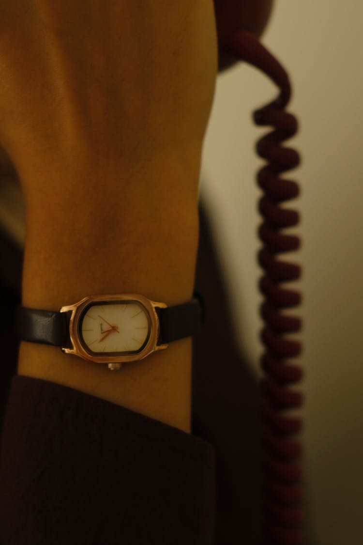 Close-up Of Person With Retro Watch Talking On Old Corded Phone