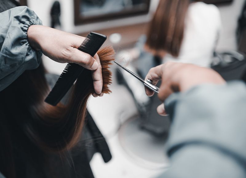 Close-up of hair cutting with scissors and comb in salon