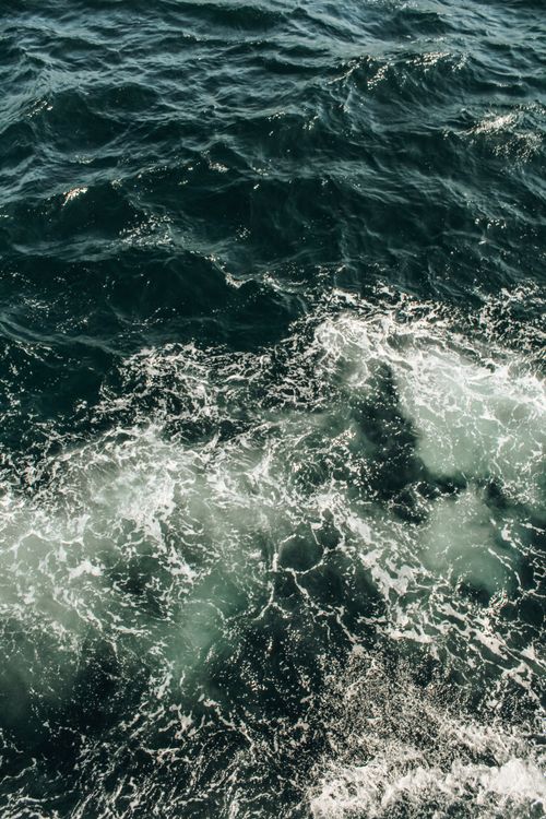 Free A stunning aerial view of ocean waves and white foam creating dynamic patterns on the surface. Stock Photo