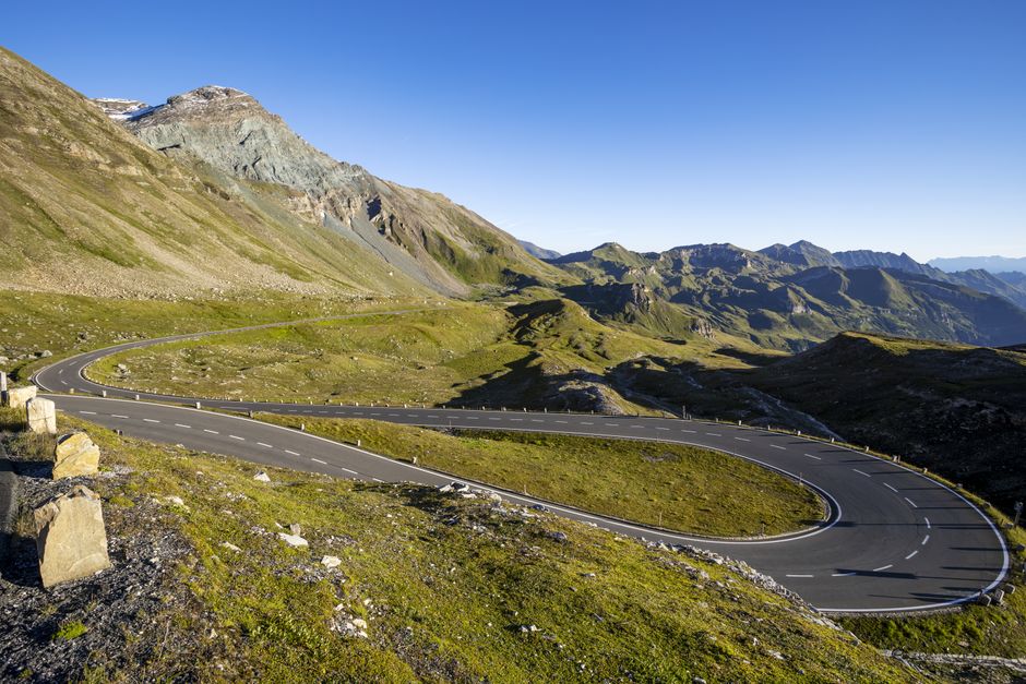 Route sinueuse traversant un paysage de montagne sous un ciel dégagé