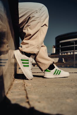 Adidas sneakers with signature green stripes worn on the street in Canada