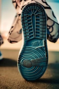 Detailed close-up of a blue shoe sole with unique patterns against an urban backdrop.