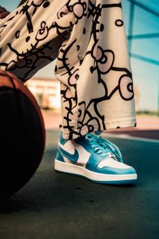 Fashionable blue sneakers paired with patterned trousers outdoors, emphasizing modern style.
