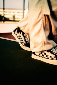 Stylish checkerboard-patterned sneakers walking on an outdoor basketball court.