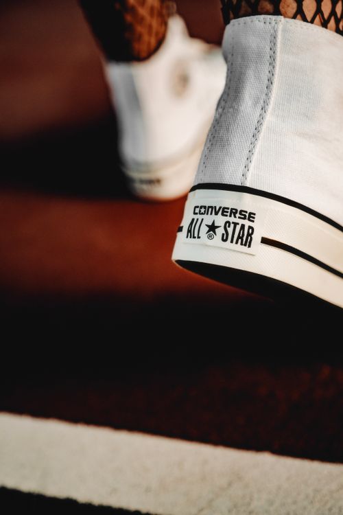 Free A detailed view of a white Converse All-Star sneaker on a red surface, showcasing its iconic design. Stock Photo